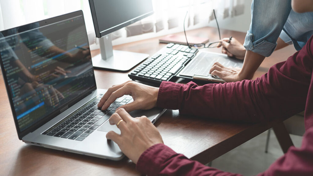 business partners coding on laptop